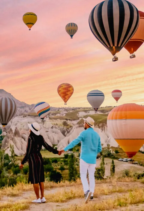Colorful hot air balloons rising over scenic landscape, ideal for bucket-list travel experiences.