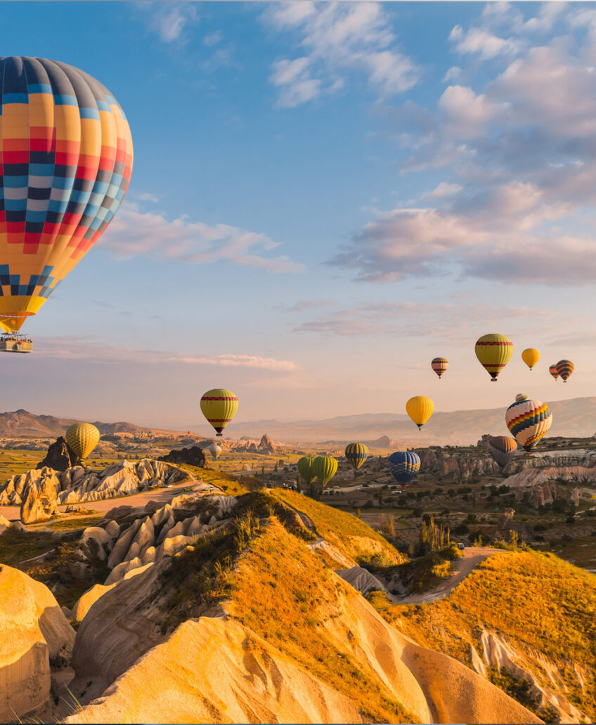 Colorful hot air balloons floating over scenic landscape during sunrise or sunset