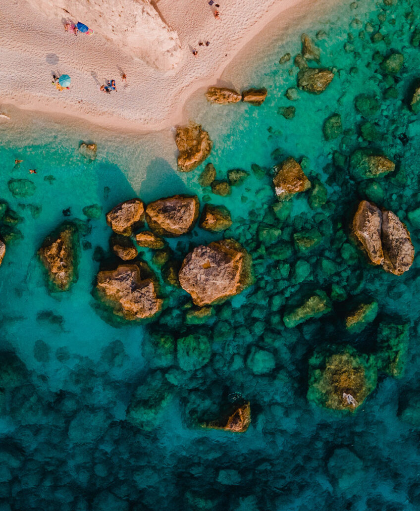 Aerial view of tropical beach with clear blue water and white sand, ideal for luxury coastal getaways.