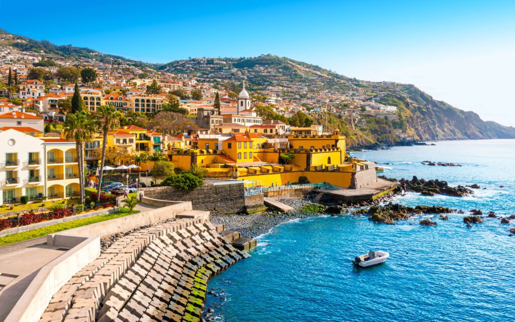 Luxury cruise ship sailing at sunset near tropical coastline