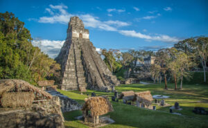 Ancient Mayan temple surrounded by lush greenery under a clear sky