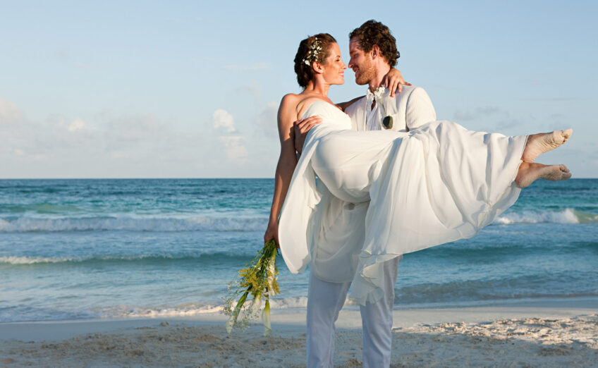 Newlyweds walking on a tropical beach, ideal for luxury honeymoon vacations and romantic destination weddings