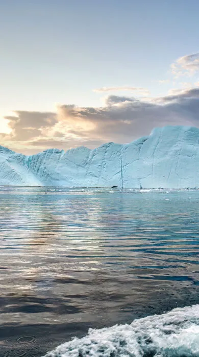 Expedition cruise ship sailing near icy polar landscapes.