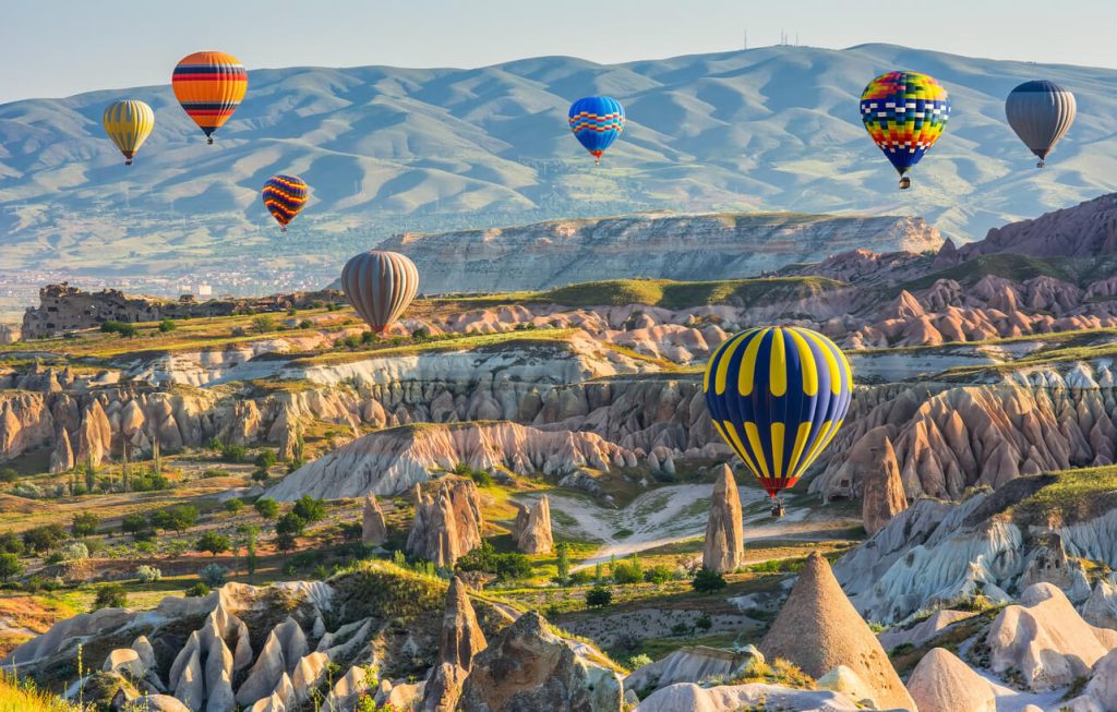 Hot air balloons drifting over the rocky landscape of Cappadocia, Turkey at sunrise — a signature Travel Adventures Unlimited experience.