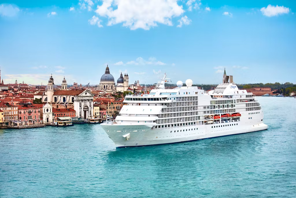 Regent Seven Seas cruise ship sailing through Venice, Italy with historic architecture in the background